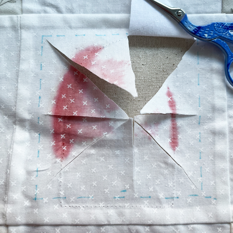 Cutting the damaged part of a quilt block out.